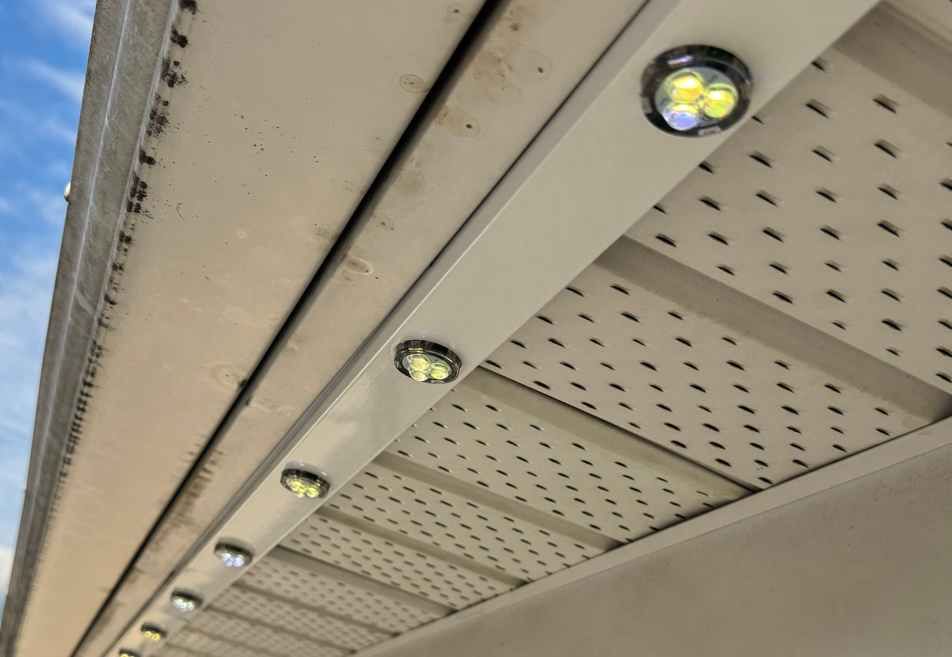 Close-up of addressable LED fixtures seated inside a colour-matched track fastened to the soffit